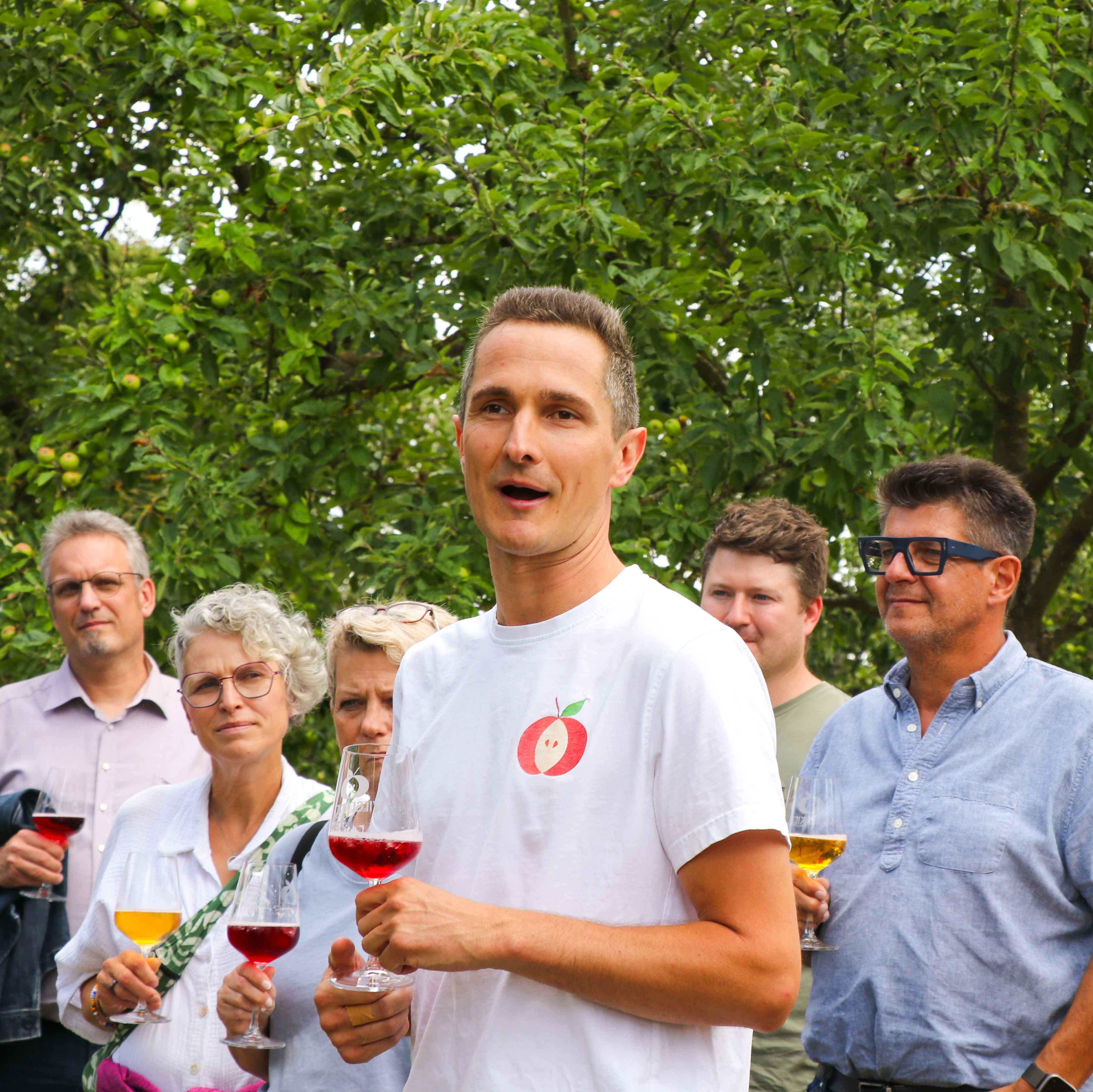 Eine Gruppe von Menschen steht im Freien und hält Weingläser.