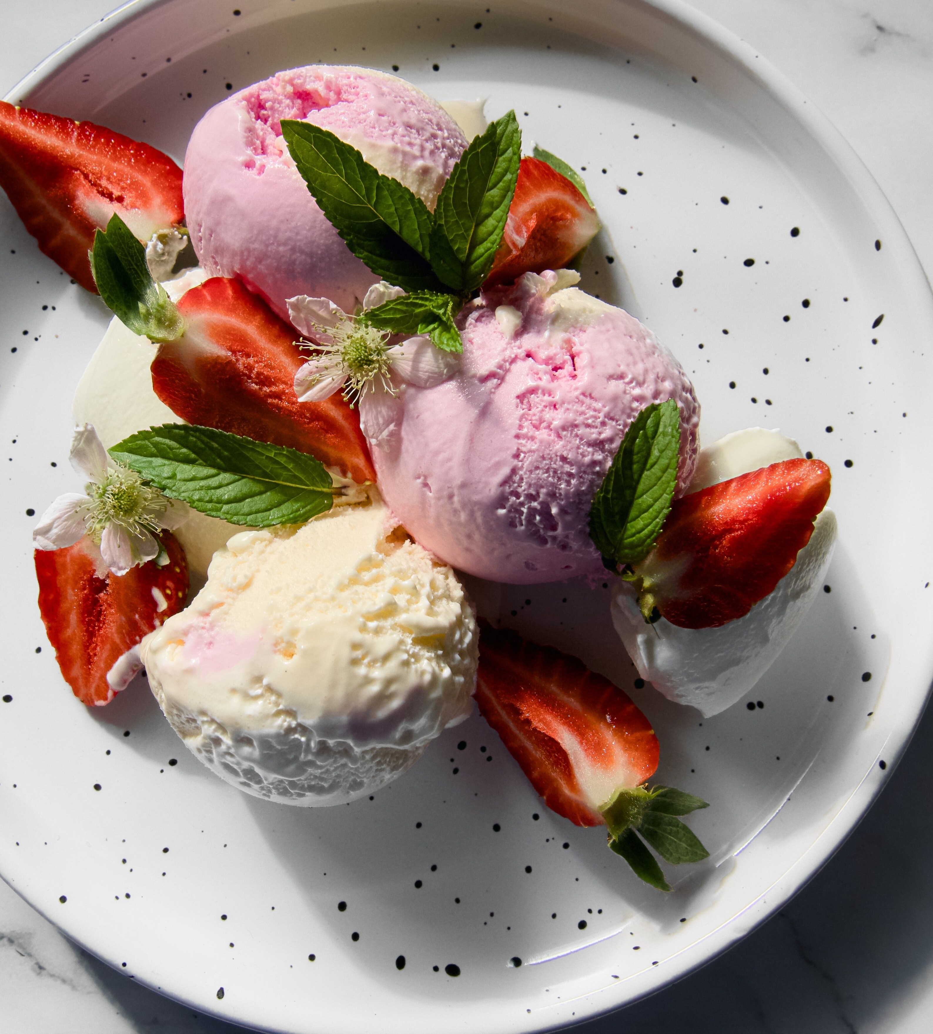Ein Teller mit Eiscreme und Erdbeeren.