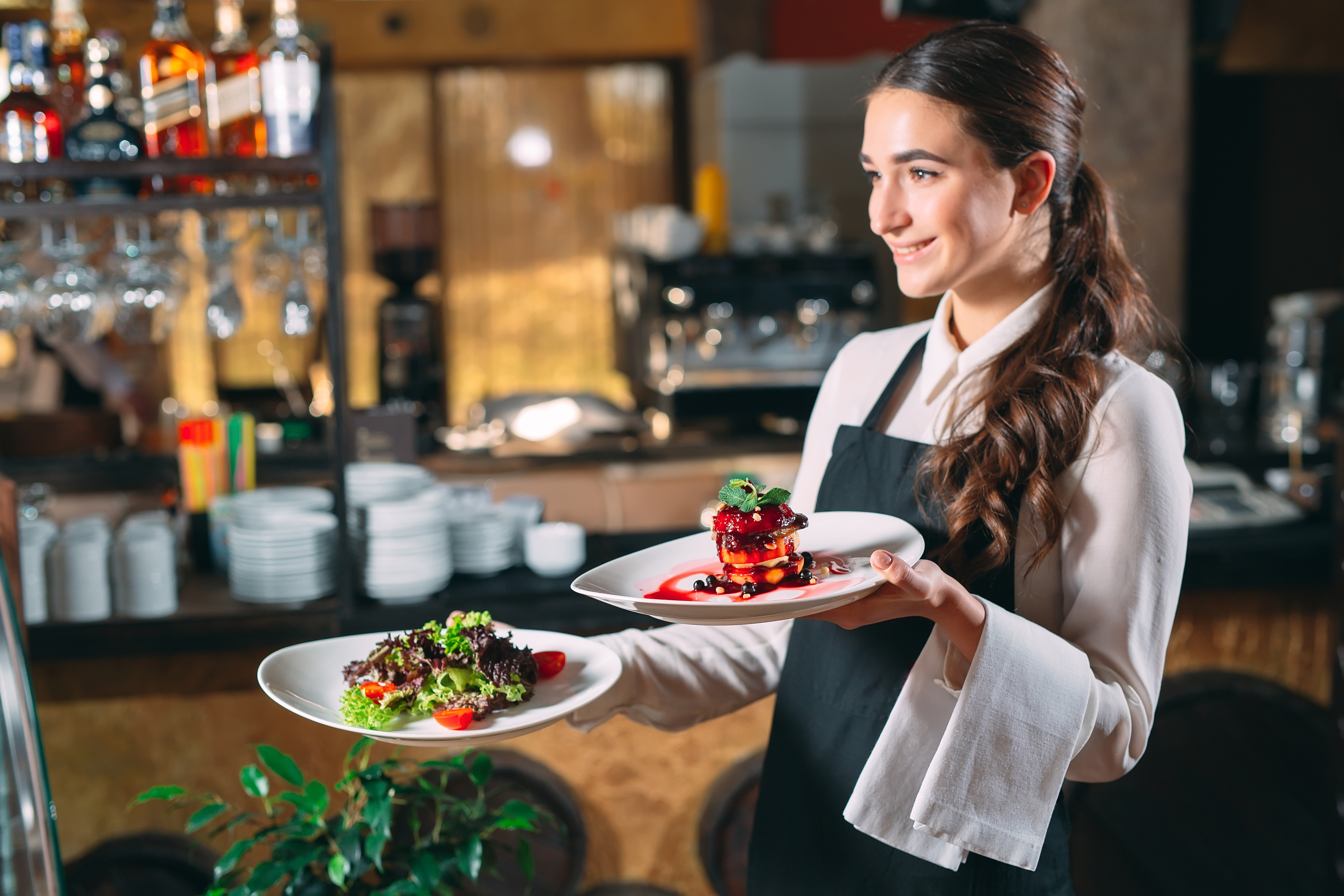 Weibliche Servicekraft trägt Teller im Restaurant