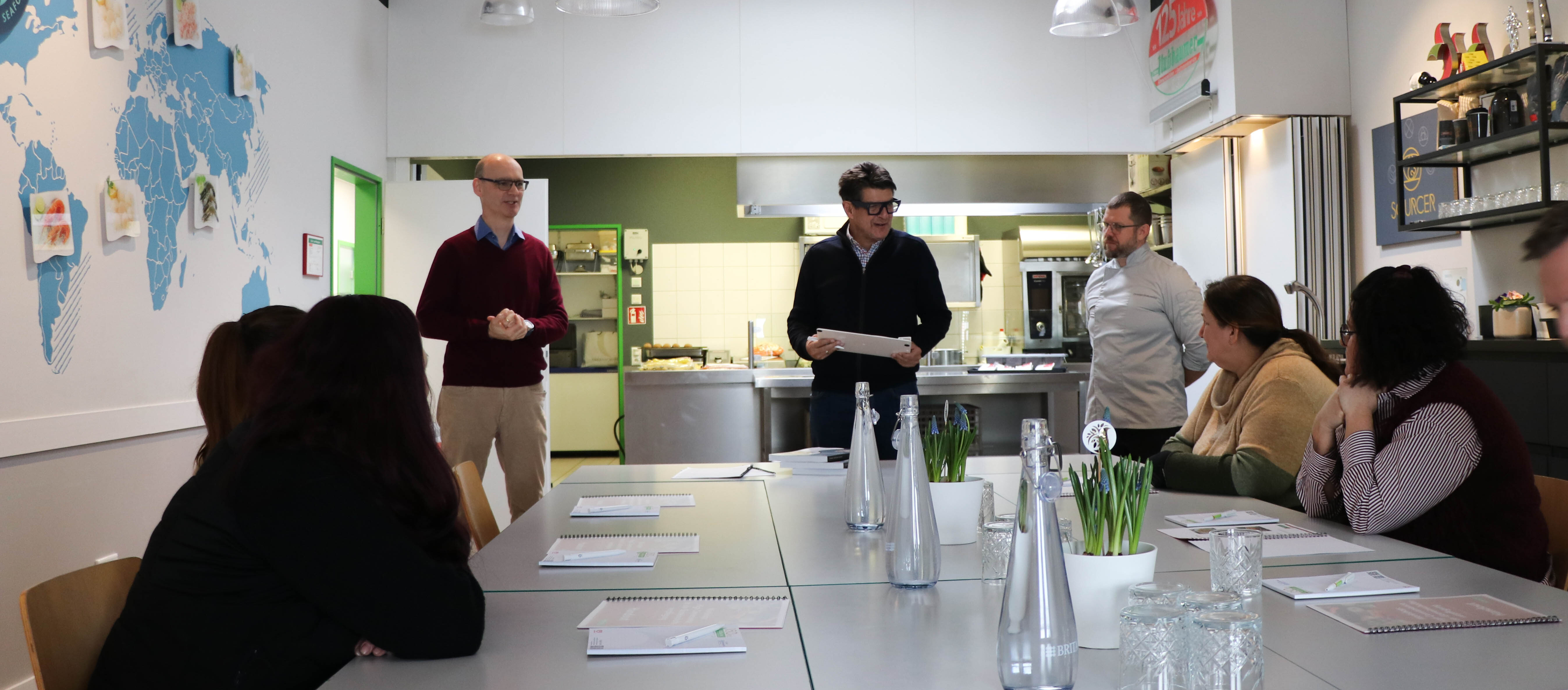 Eine Gruppe von Menschen in einem Raum mit Projektionsleinwand.