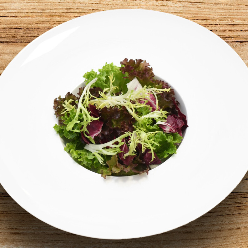 Ein Teller Salat auf einem Holztisch.