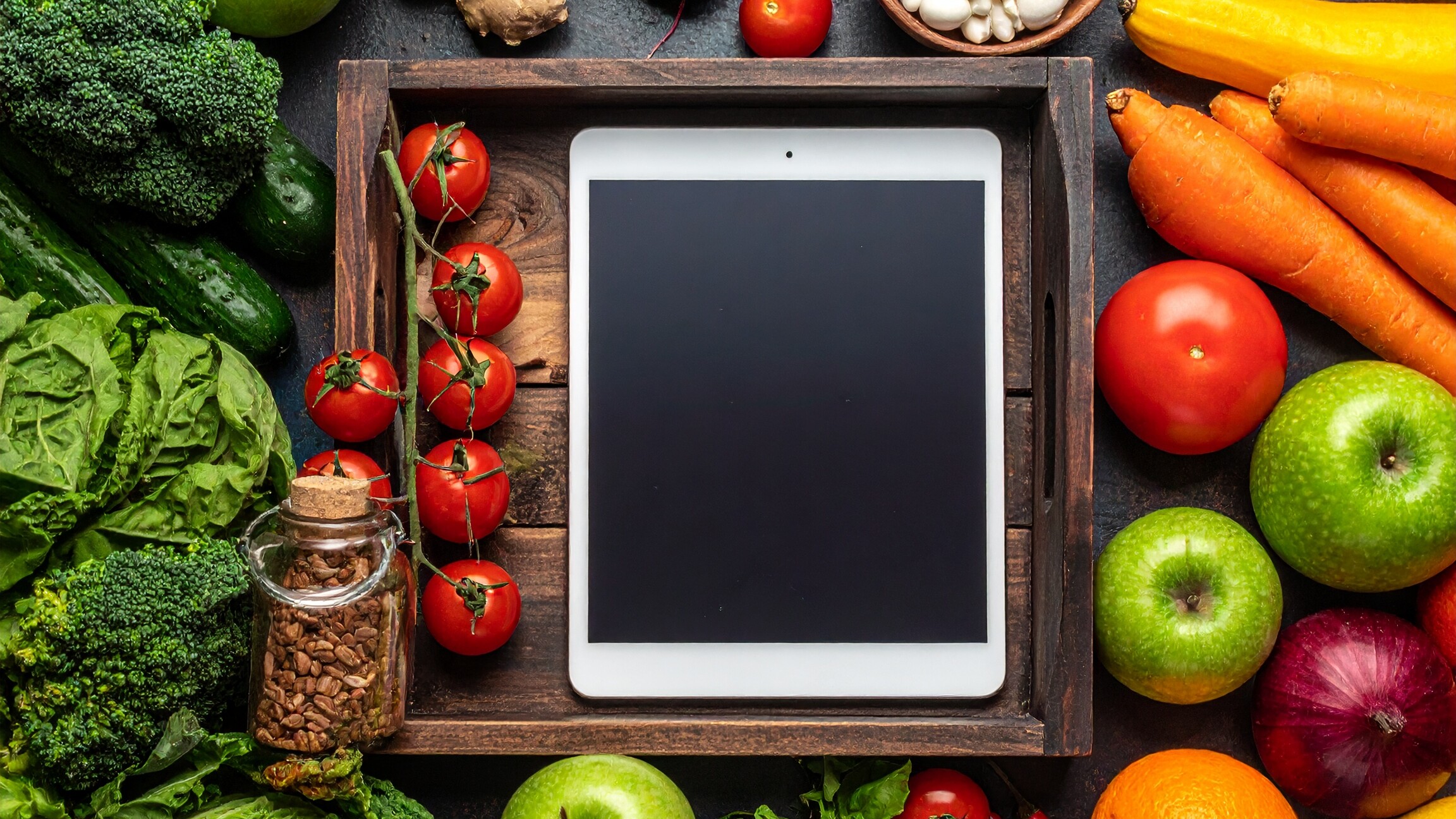 Ein Tablet umgeben von verschiedenen Gemüsesorten.