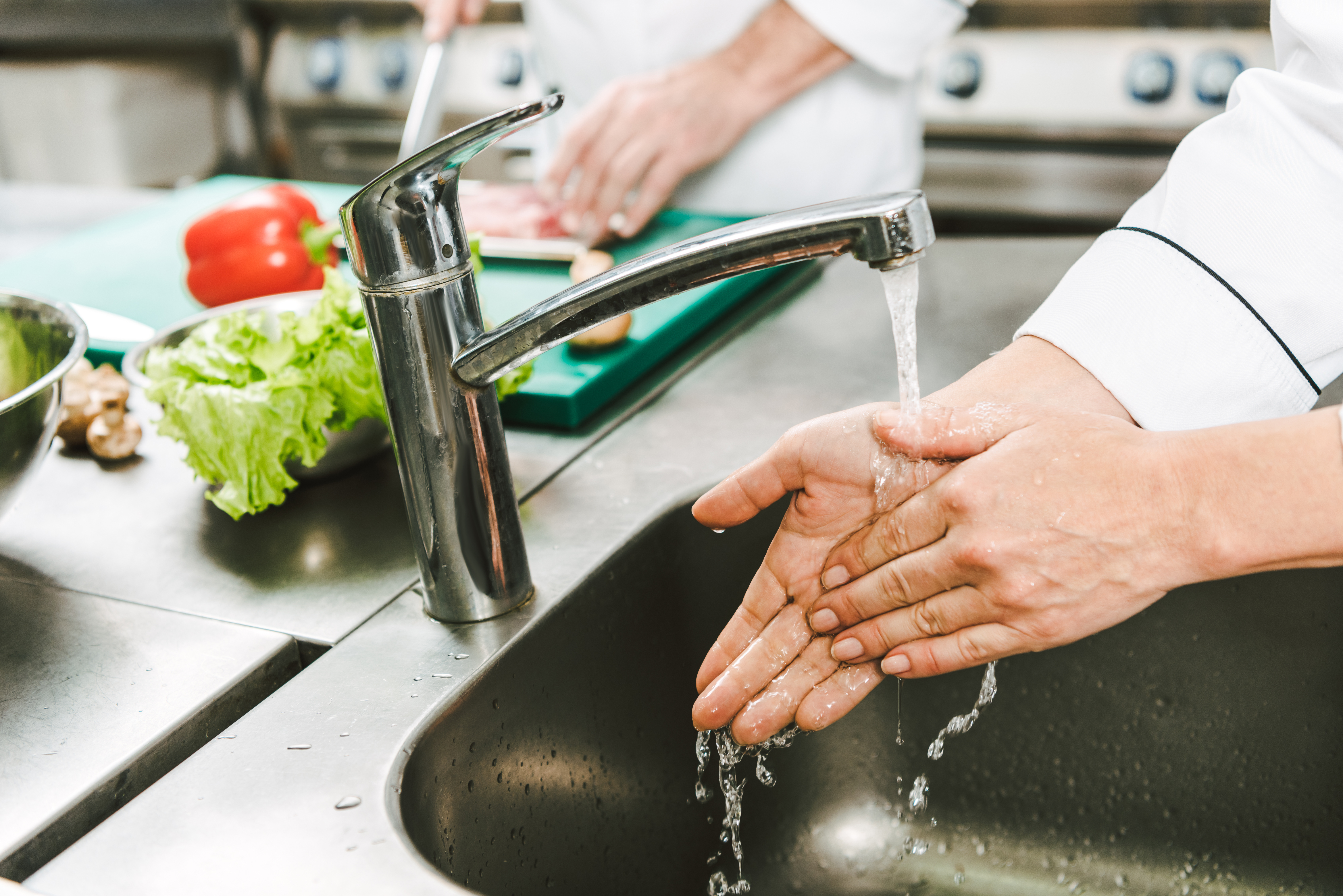 Männlicher Küchenmitarbeiter wäscht Hände