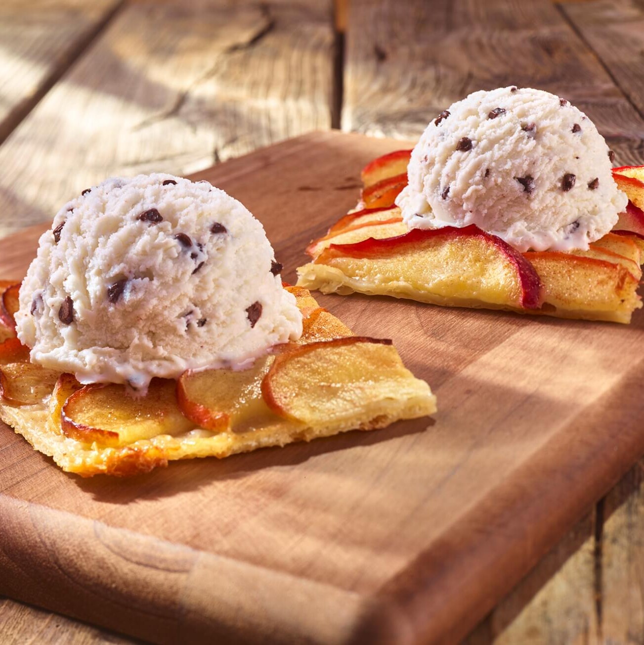 Apfel-Flammkuchen mit Walnuss-Eis auf einem Holzbrett angerichtet