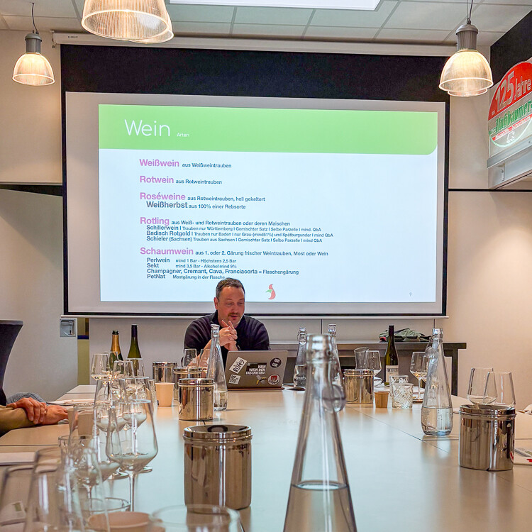 Ein Mann sitzt an einem Tisch vor einer Projektionsleinwand.