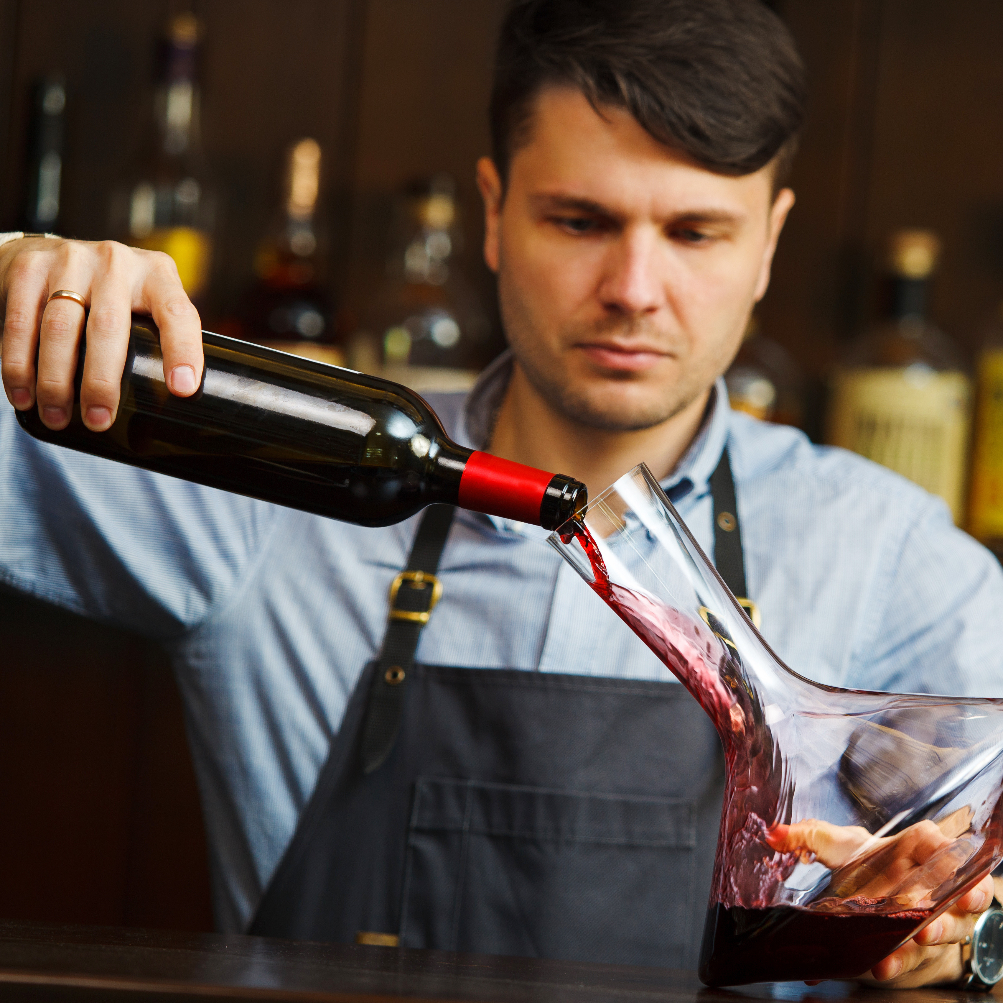 Mann gießt Rotwein in einen Dekanter