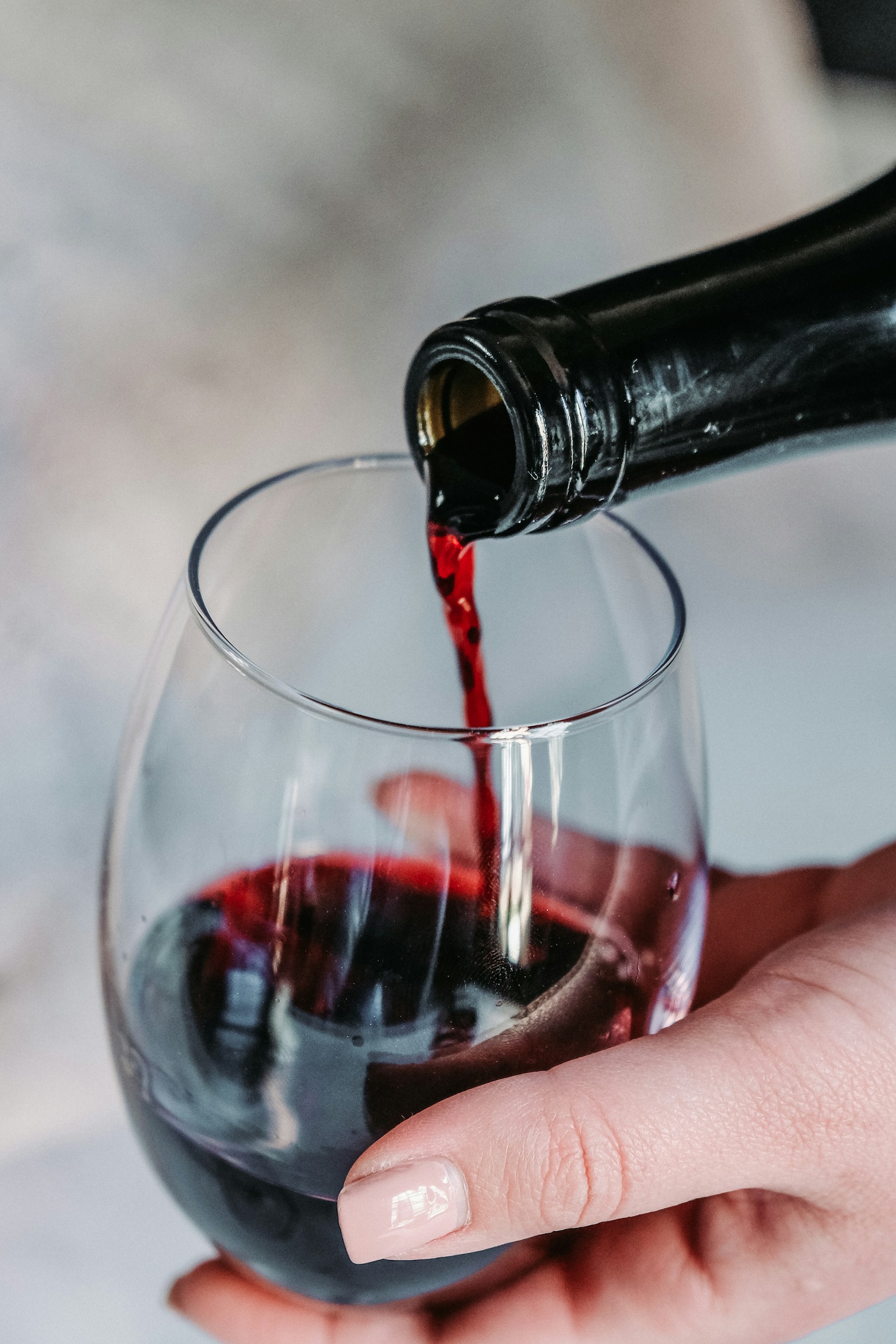 Eine Person schenkt Rotwein in ein Glas ein. Eine Person schenkt Rotwein in ein Glas ein.