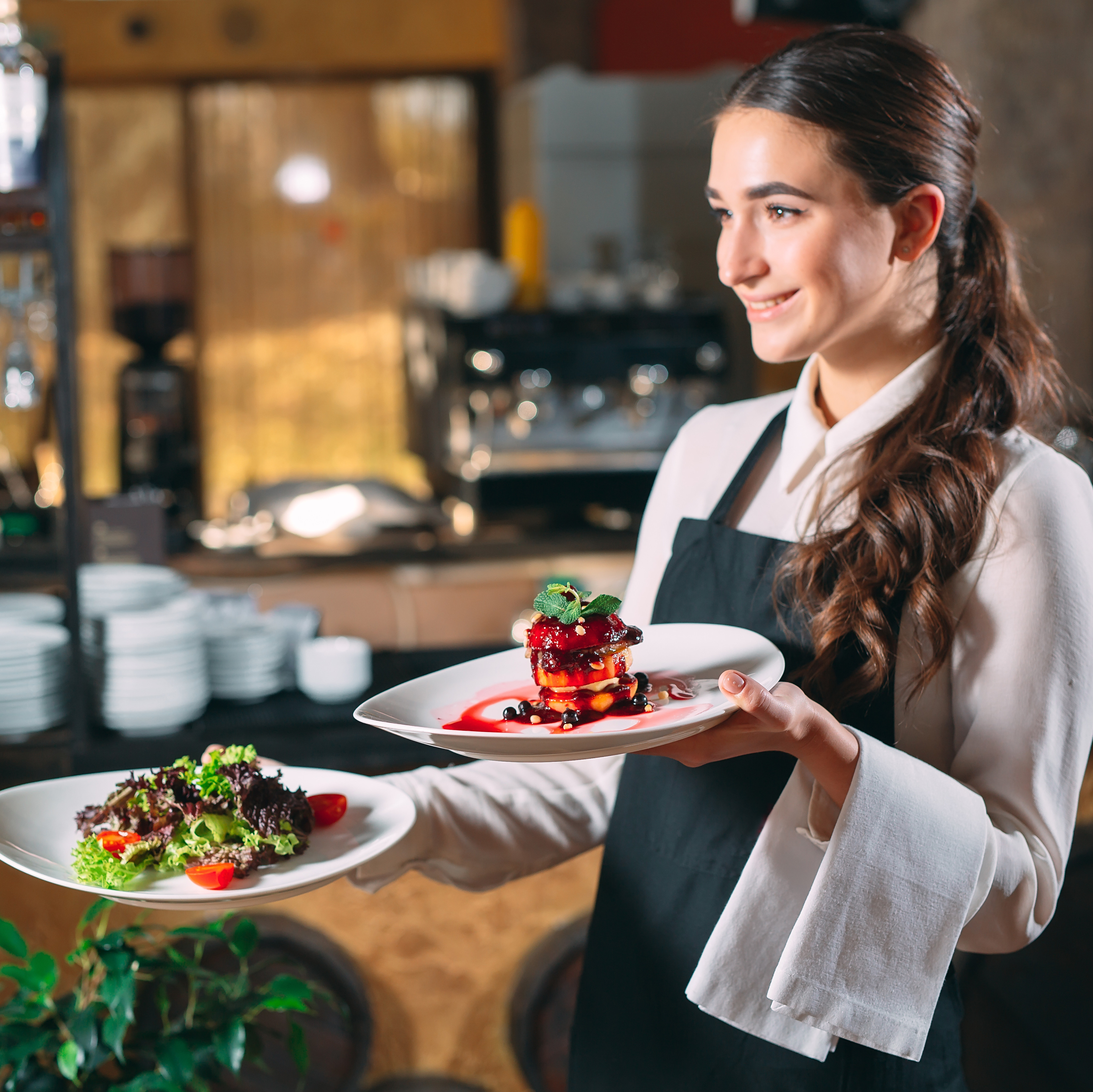 Weibliche Servicekraft trägt Teller im Restaurant