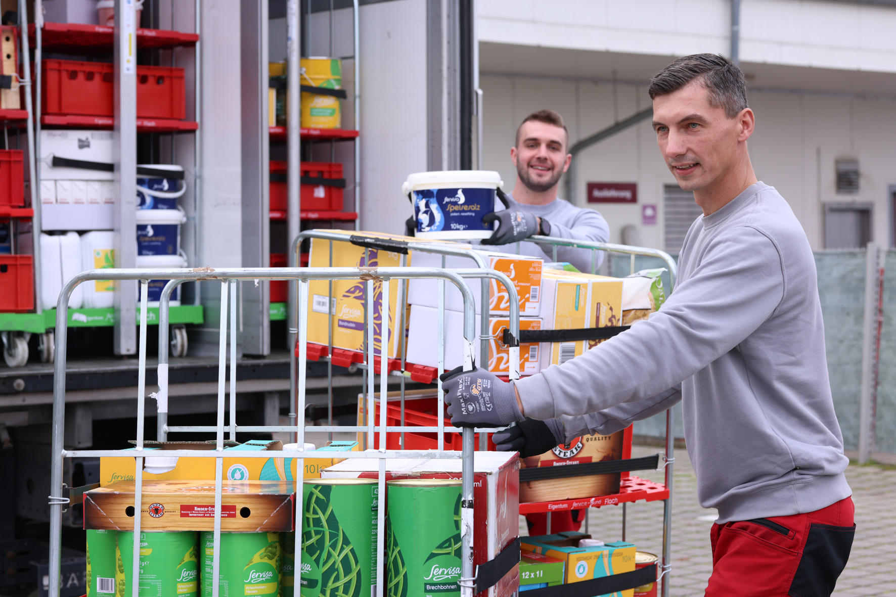 Mitarbeiter beim Ausladen eines Rollis aus dem LKW