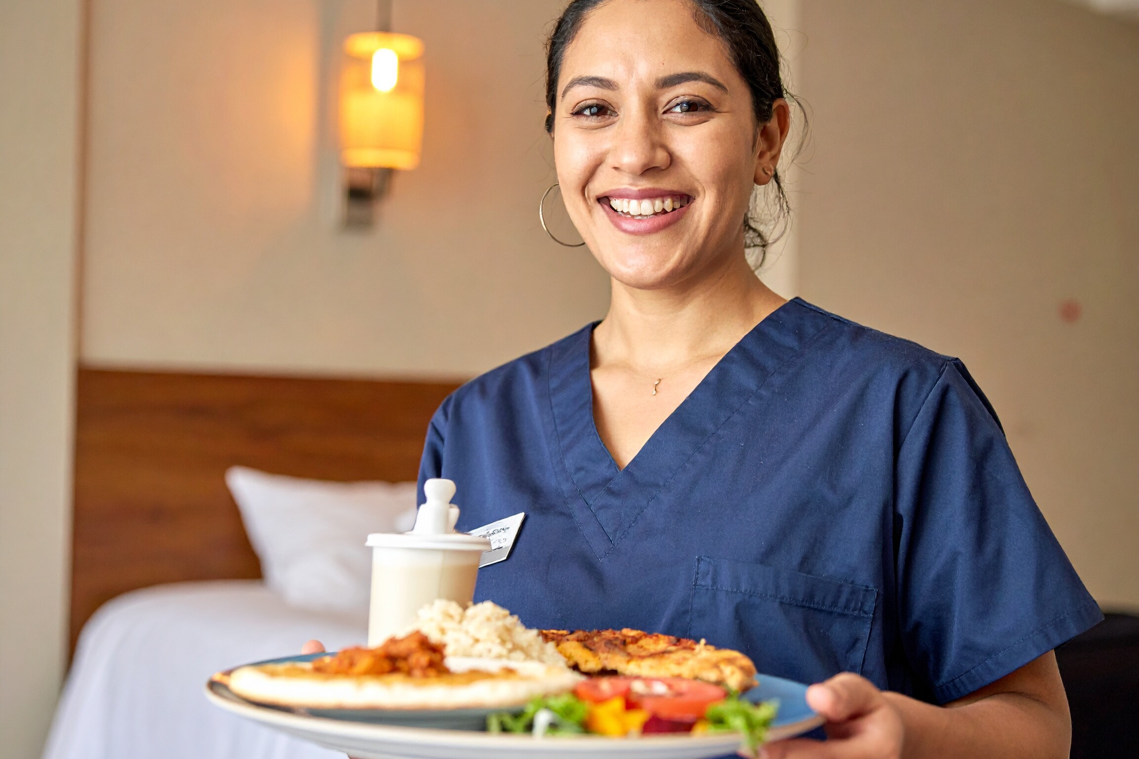 Eine Frau in Arbeitskleidung hält einen Teller mit Essen. Eine Frau in Arbeitskleidung hält einen Teller mit Essen.