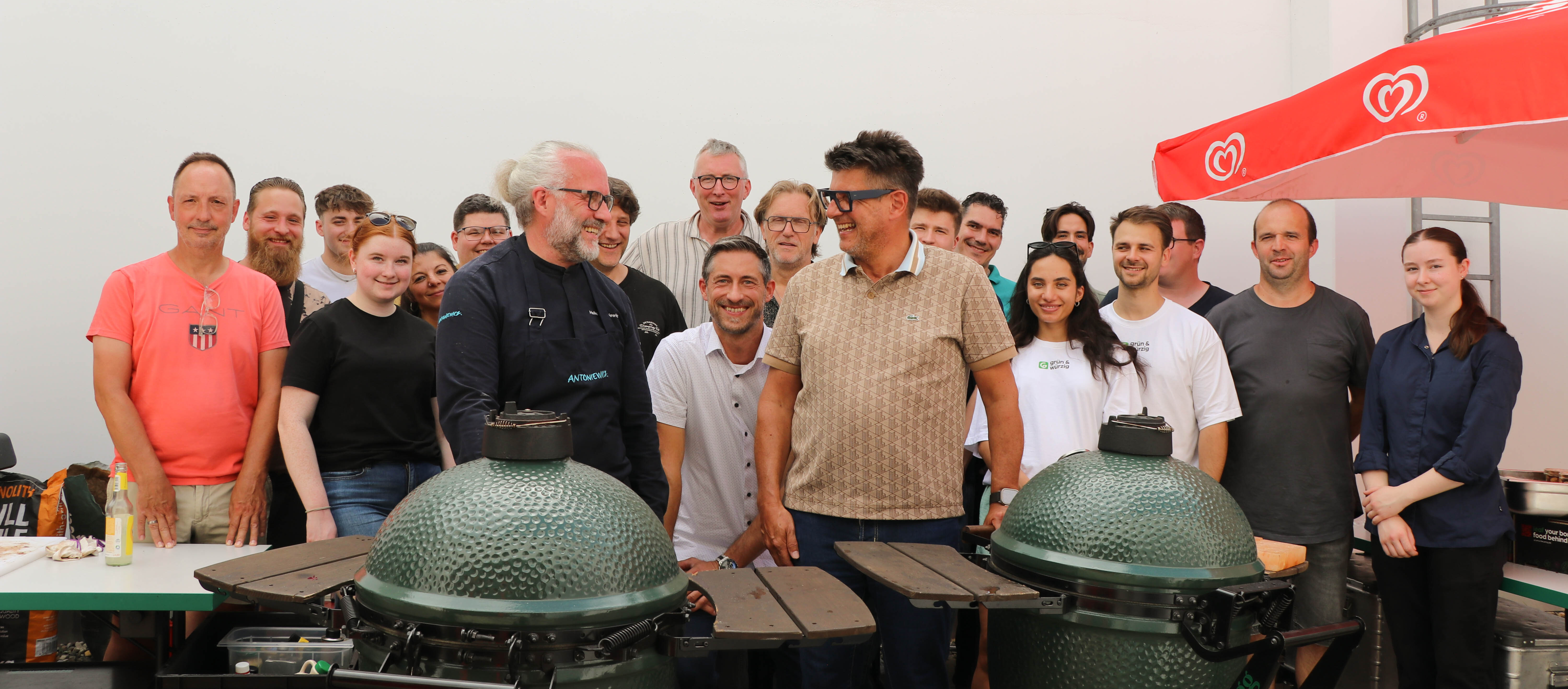Eine Gruppe von Menschen steht um einen großen grünen Grill.