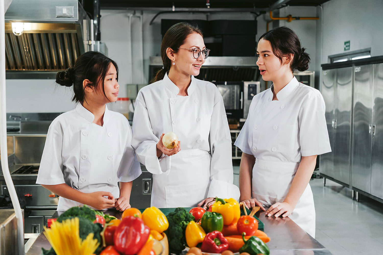 3 Frauen in einer Küche Eine Gruppe von Frauen in weißen Uniformen steht in einer Küche.