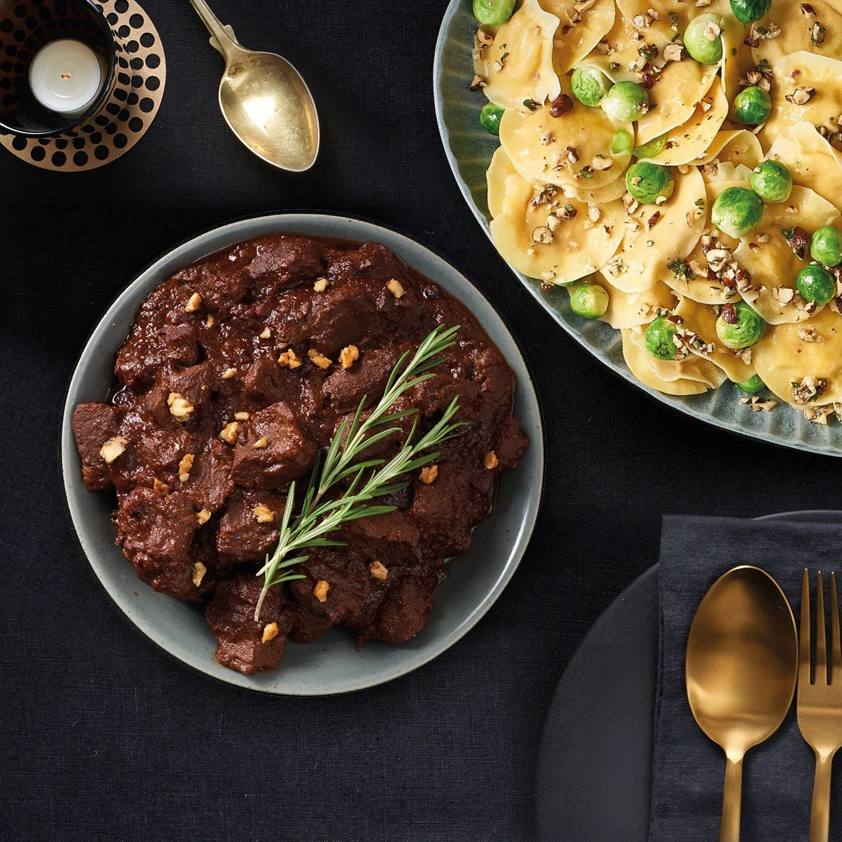 Geschmorter Hirsch mit gebratenen Agnolotti alla Zuccha und Rosenkohlherzen auf mehreren Tellern angerichtet