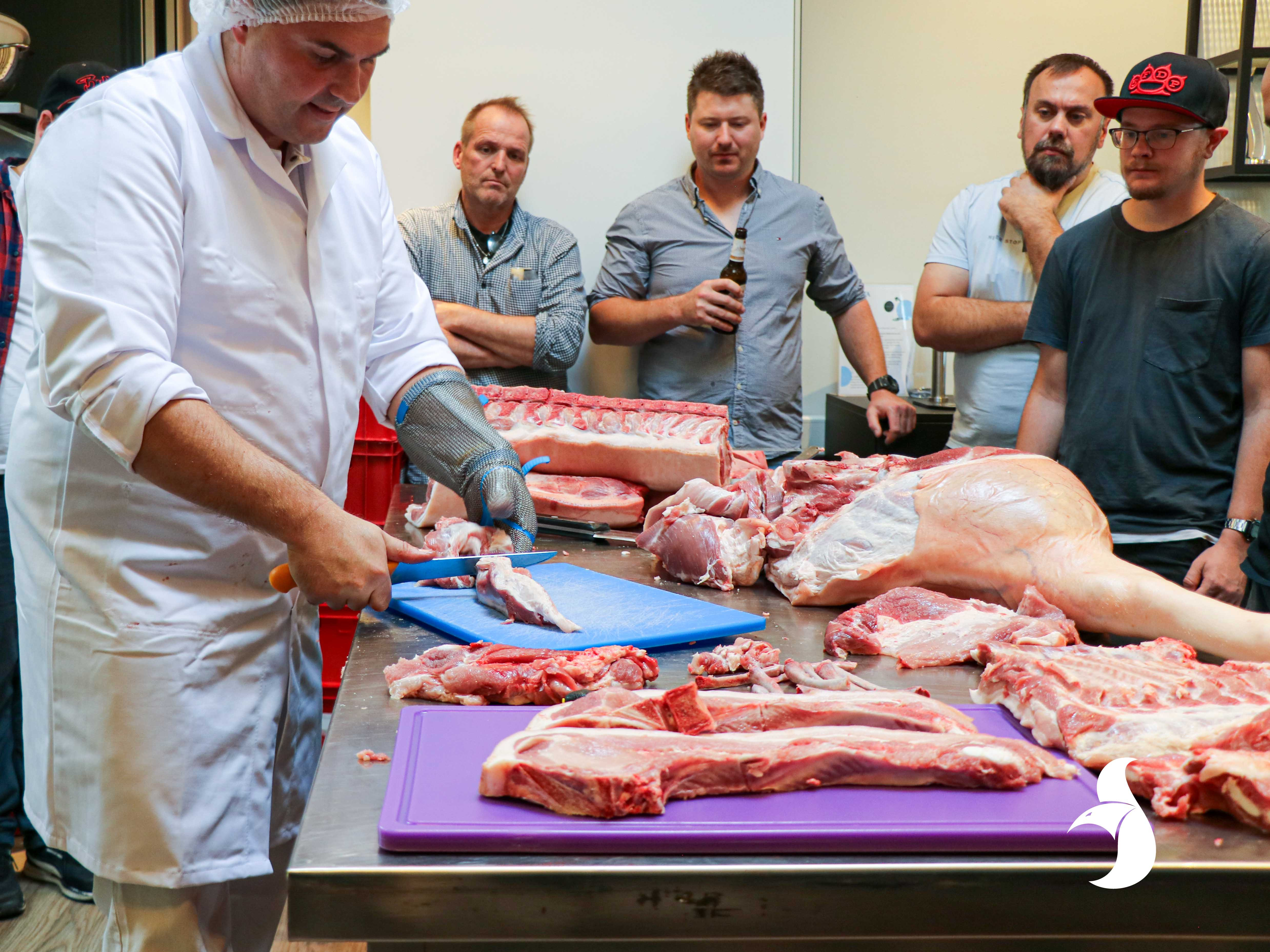 Workshop-Teilnehmer stehen um die Theke und schauen das Fleisch an