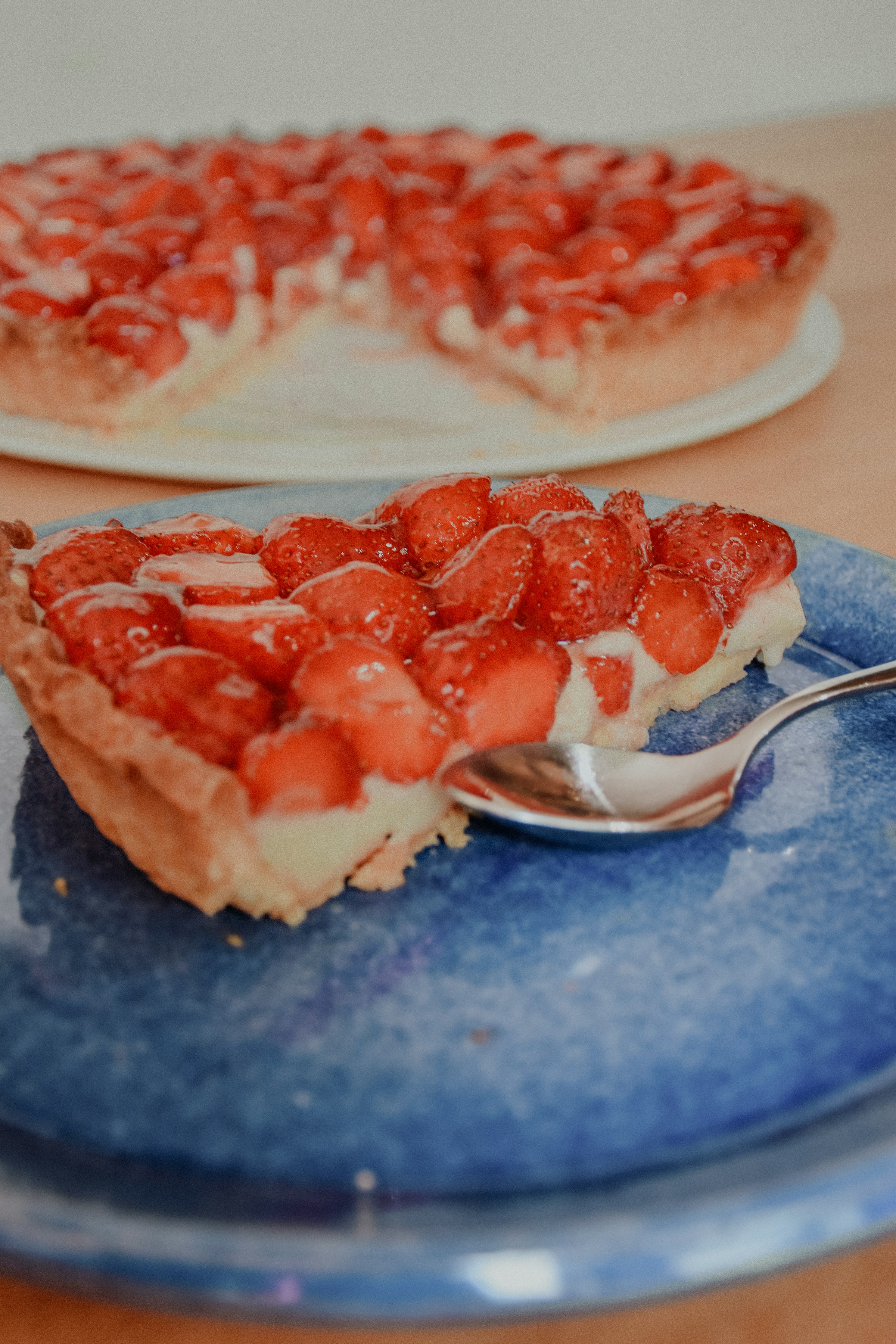 Ein Stück Erdbeerkuchen mit einem Löffel auf einem blauen Teller