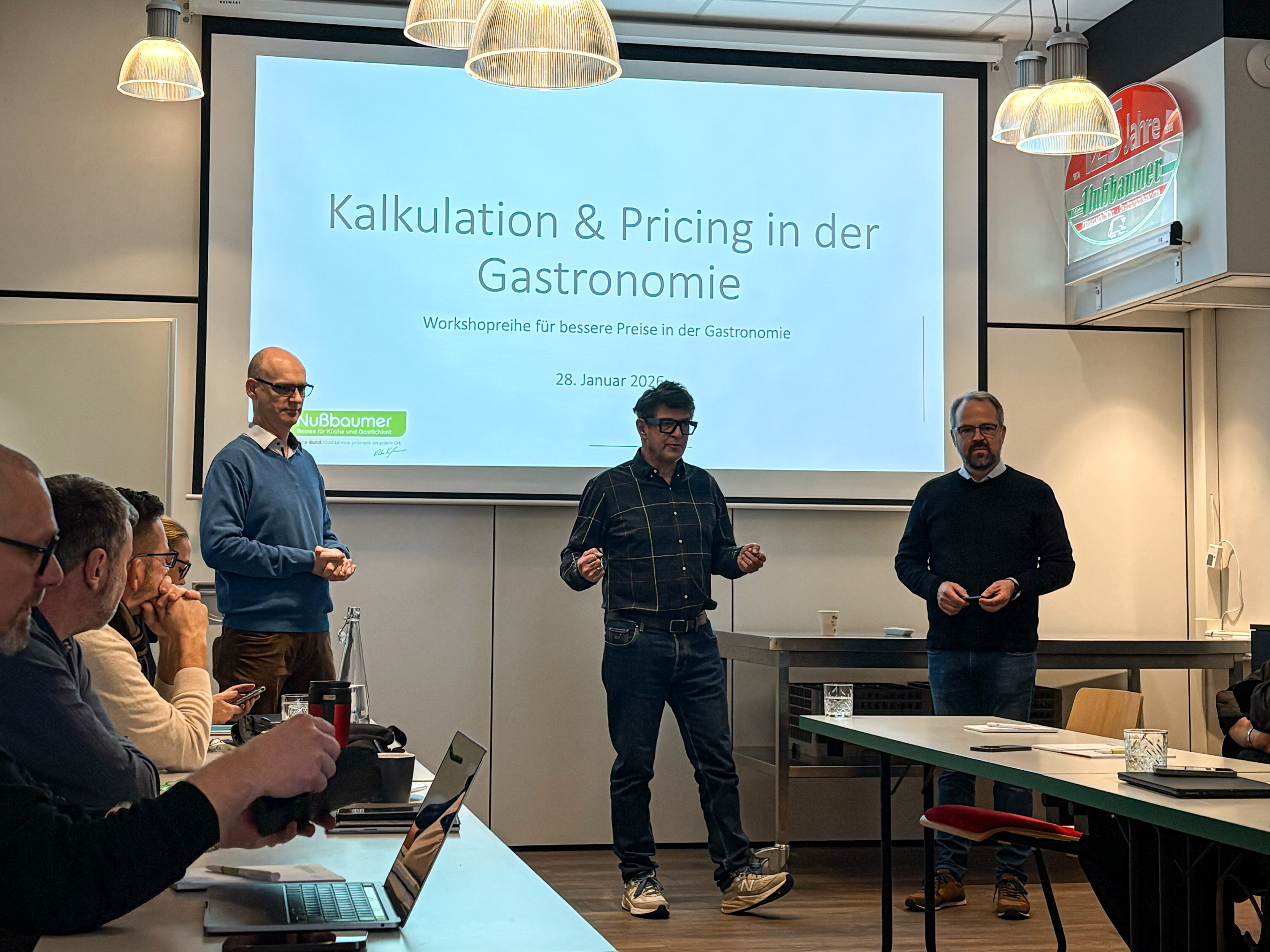 Vortrag "Preismanagement" Eine Gruppe von Menschen in einem Raum mit Projektionsleinwand.