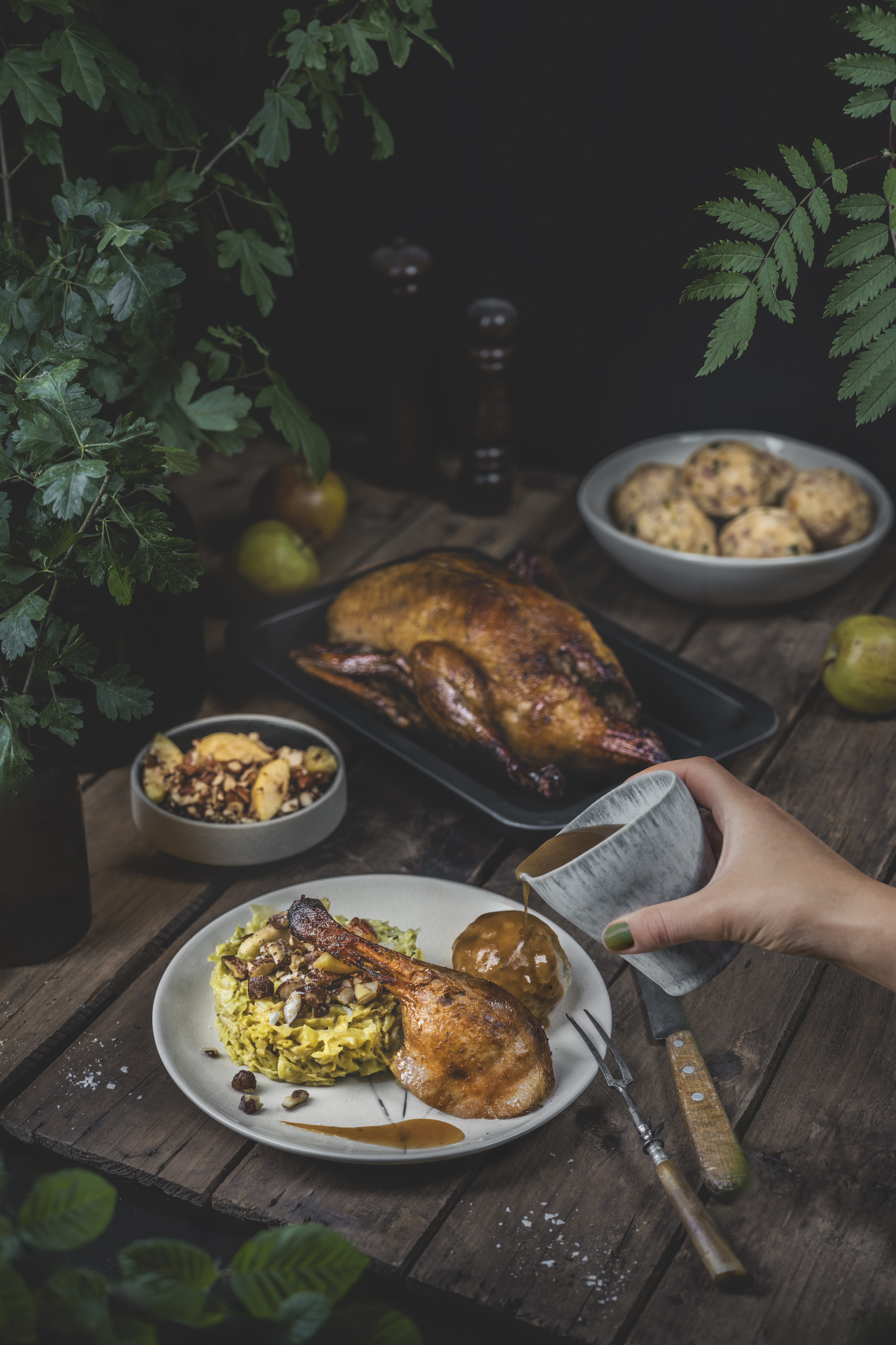 Eine Person gießt Sauce auf einen Teller mit Essen. Eine Person gießt Sauce auf einen Teller mit Essen.