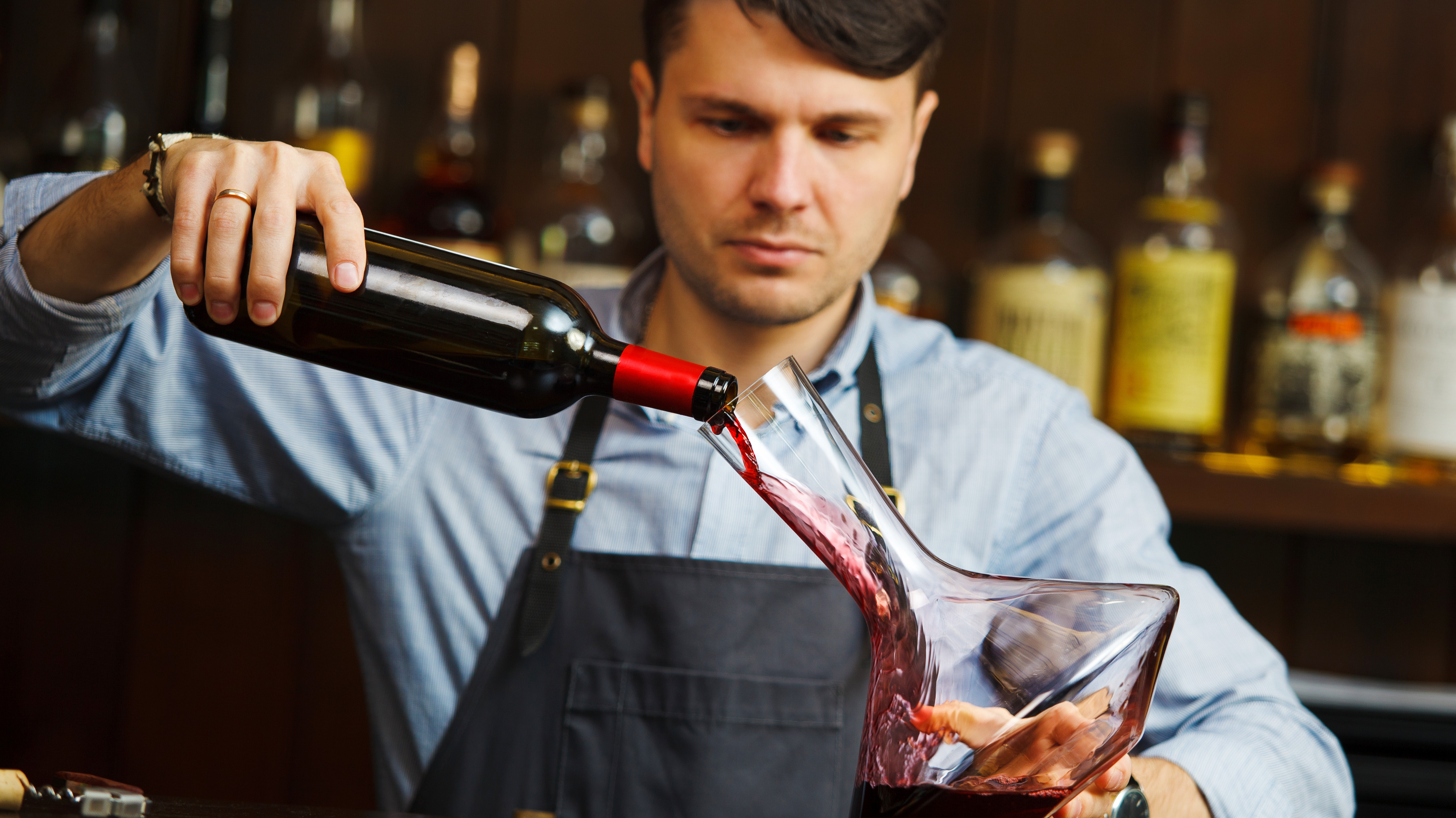 Dekantieren Ein Mann gießt Rotwein in eine Karaffe.