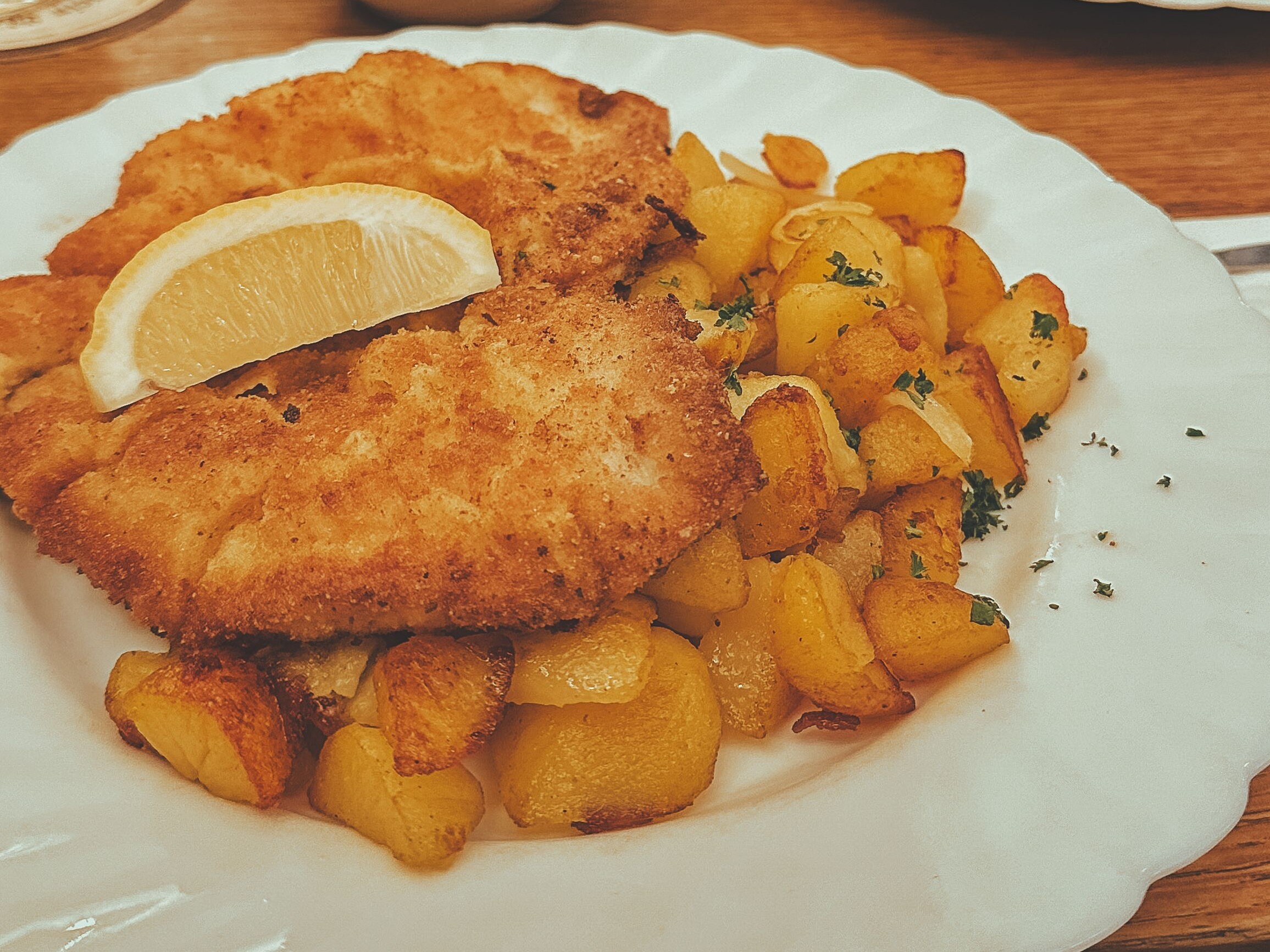 Ein Teller mit Schnitzel und Pommes auf einem Tisch.