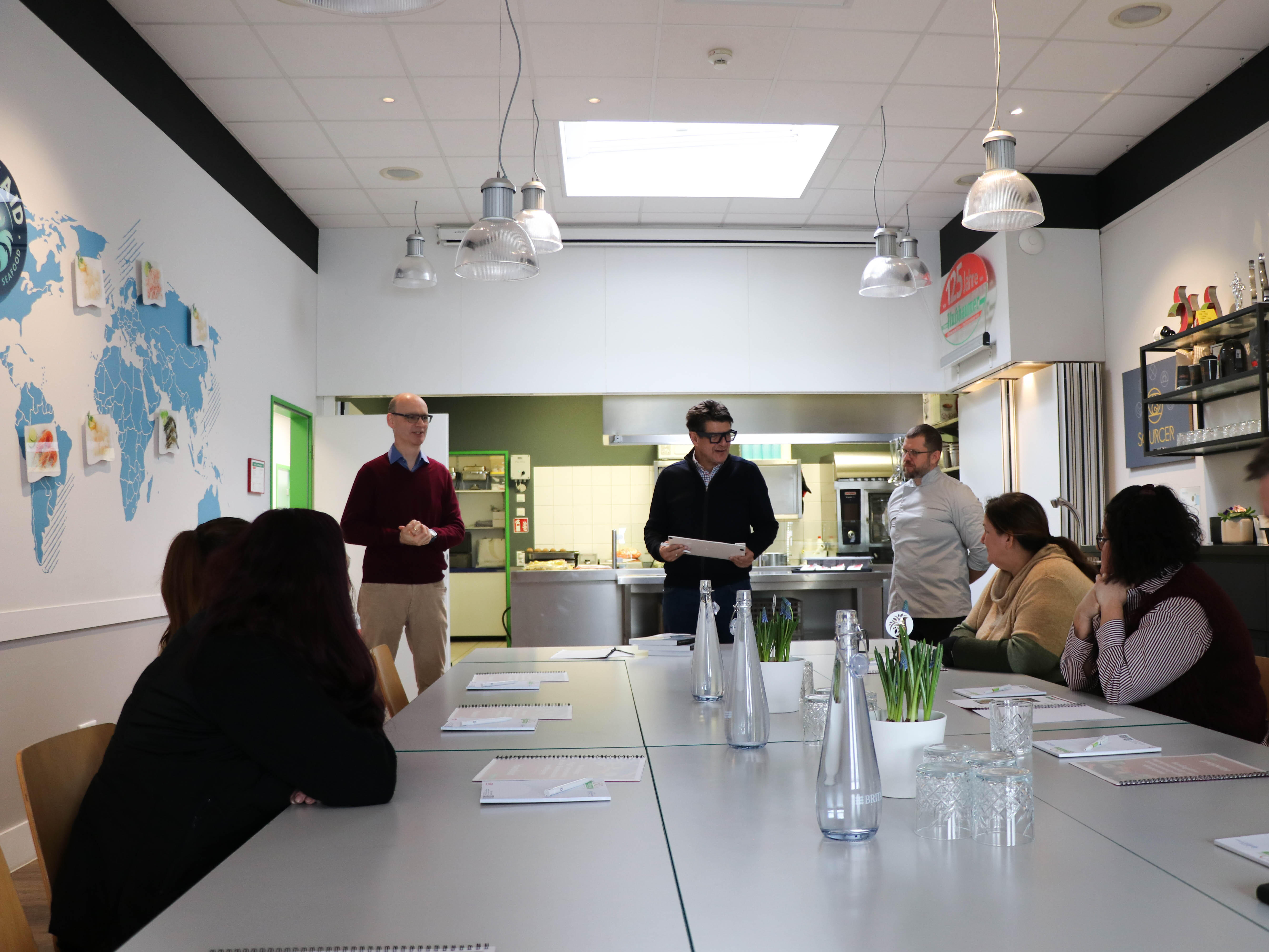 Eine Gruppe von Menschen in einem Raum mit Projektionsleinwand.