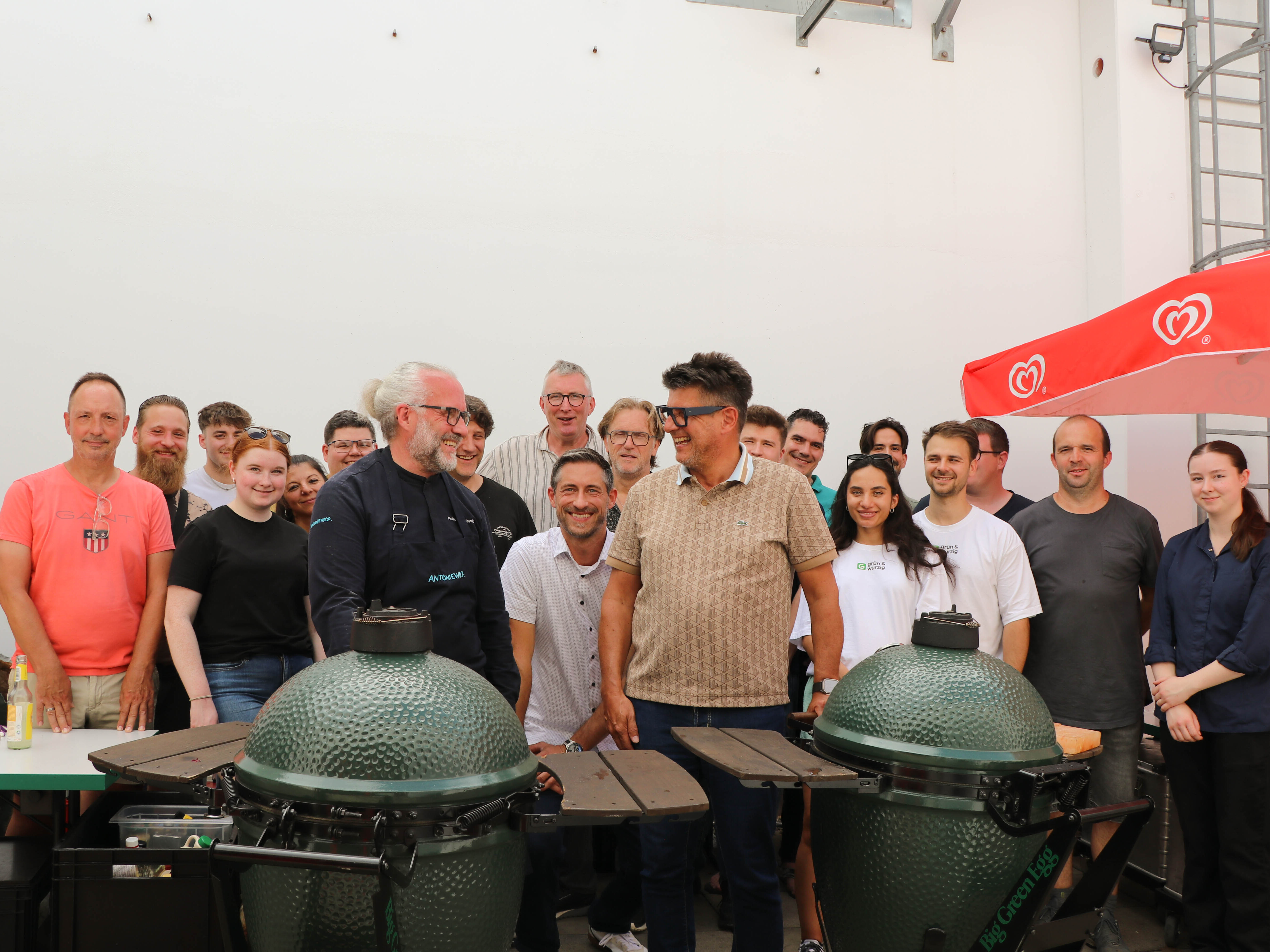 Eine Gruppe von Menschen steht um einen großen grünen Grill.