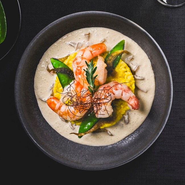 Wildgarnelen auf Safranrisotto mit Zuckerschoten angerichtet auf einem Teller