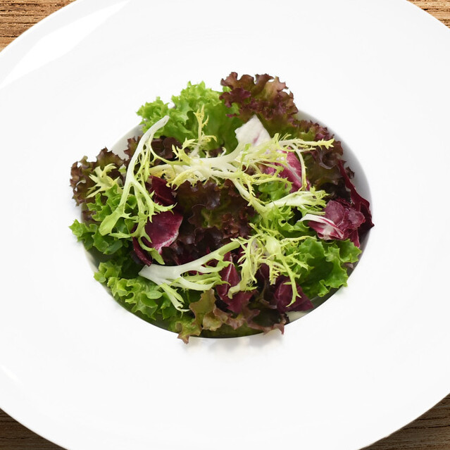 Ein Teller mit Salat auf einem Holztisch.